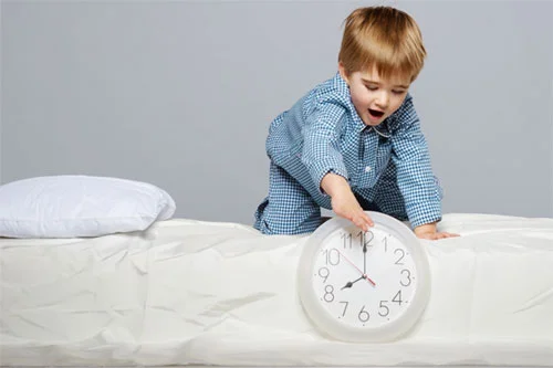 Child on bed playing with clock